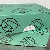 Green box with black geometric patterns on a gray surface